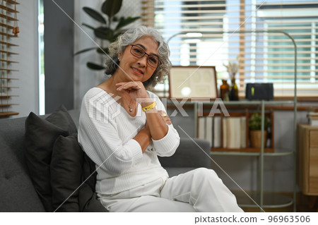 Portrait of middle aged woman sitting comfortable couch at home and smiling to camera. Retirement, enjoy life concept 96963506