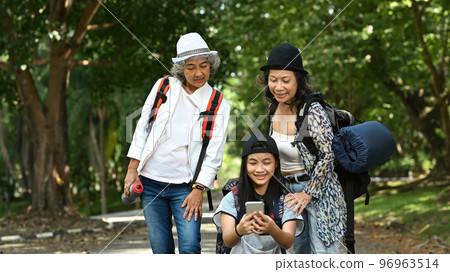 Happy middle aged women and asian girl taking selfie on smart phone while walking in green city park 96963514