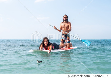 Sea woman and man on sup. Silhouette of happy young woman and man, surfing on SUP board, confident paddling through water surface. Idyllic sunset. Active lifestyle at sea or river. Slow motion Sea woman and man on sup. Silhouette of happy young woman and man, surfing on SUP board, confident paddling through water surface. Idyllic sunset. Active lifestyle at sea or river. Slow motion 96965193