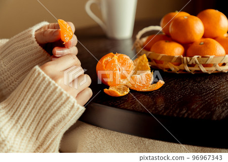 A woman eating mandarin oranges on a kotatsu in winter 96967343