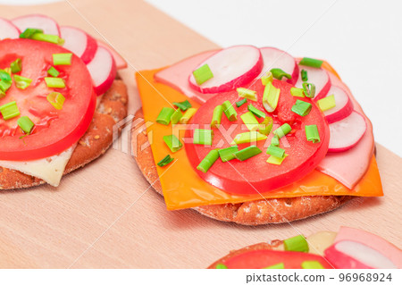 Crispy Cracker Sandwiches with Tomato, Sausage, Cheese, Green Onions and Radish 96968924