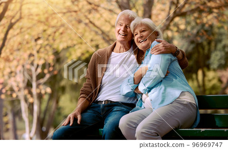 Senior couple, park bench and happy while sitting together in retirement for freedom, peace and calm with a smile and happiness in nature. Old man and woman outdoor to relax while on vacation Senior couple, park bench and happy while sitting together in retirement for freedom, peace and calm with a smile and happiness in nature. Old man and woman outdoor to relax while on vacation 96969747