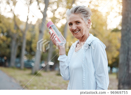 Water, fitness and park with a senior woman holding a bottle during an exercise or workout for a healthy lifestyle. Portrait, training and wellness with a mature female exercising outdoor in a garden 96969755