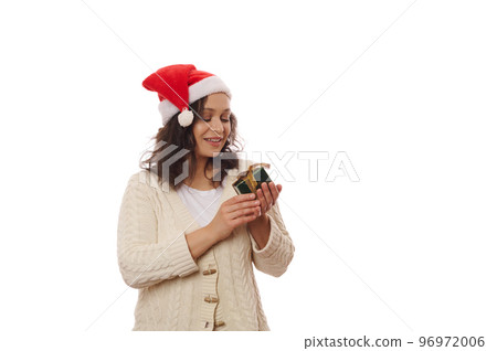 Attractive African American woman wearing santa hat, waiting to open gift box with happy present for Christmas , isolated on white background with copy advertising space. Christmastime. Winter events Attractive African American woman wearing santa hat, waiting to open gift box with happy present for Christmas , isolated on white background with copy advertising space. Christmastime. Winter events 96972006