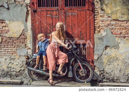 Mom and son on an old motorcycle. Penang 96972824