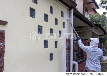 Painter worker adding undercoat foundation paint onto wall with roller at residential building in renovation Painter worker adding undercoat foundation paint onto wall with roller at residential building in renovation 96974602
