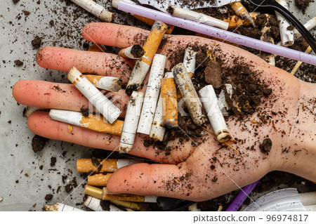 Close up hand holding pile of cigarettes with dirt. Concept of enviroment pollution. Close up hand holding pile of cigarettes with dirt. Concept of enviroment pollution. 96974817