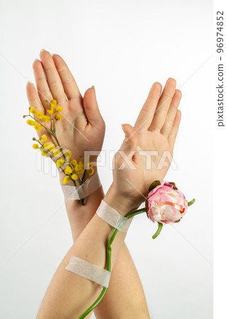 Two crossed female forearms with patched flowers. Vertical shot white background. Two crossed female forearms with patched flowers. Vertical shot white background. 96974852