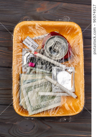 Top view teenage stuff wrapped in plastic. Money with condom and cigarettes. 96974917