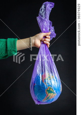 Female hand holding plastic bag with world globe. Isolated on black background. Female hand holding plastic bag with world globe. Isolated on black background. 96974929