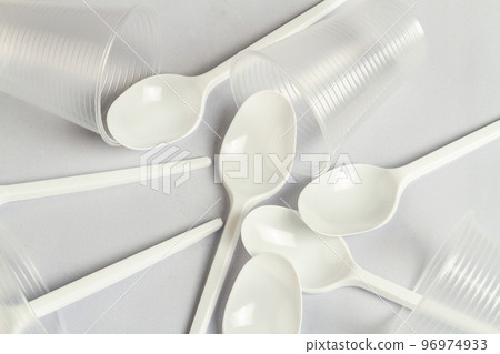 Disposable plastic spoons and cups on white. Close up of utensils. Disposable plastic spoons and cups on white. Close up of utensils. 96974933