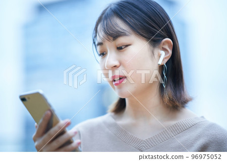 A young woman watching a smartphone A young woman watching a smartphone 96975052