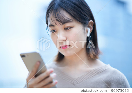 A young woman watching a smartphone A young woman watching a smartphone 96975053