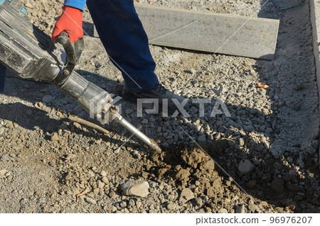Concrete surface of road was dug and drilled by construction road workers using jackhammer Concrete surface of road was dug and drilled by construction road workers using jackhammer 96976207