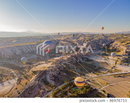 Colorful hot air balloons flying over at fairy chimneys valley in Nevsehir, Goreme, Cappadocia Turkey. Spectacular panoramic drone view of the underground city and ballooning tourism. High quality 96976733