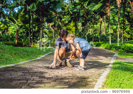 Dad and son playing with drone, man and boy playing with flying drone in sunny autumn garden, happy young boy and father playing with unmanned aerial vehicle quadrocopter, spending time together Dad and son playing with drone, man and boy playing with flying drone in sunny autumn garden, happy young boy and father playing with unmanned aerial vehicle quadrocopter, spending time together 96976999