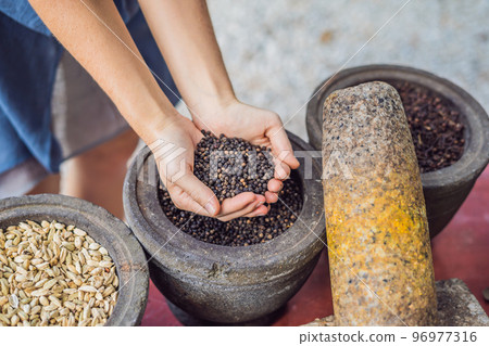 Black pepper in female hands on a background of spices Black pepper in female hands on a background of spices 96977316