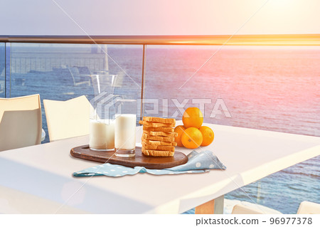 Table for two served with a breakfast on outdoor hotel balcony with a sea view. 96977378