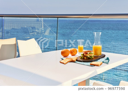 Table for two served with a breakfast on outdoor hotel balcony with a sea view. 96977398