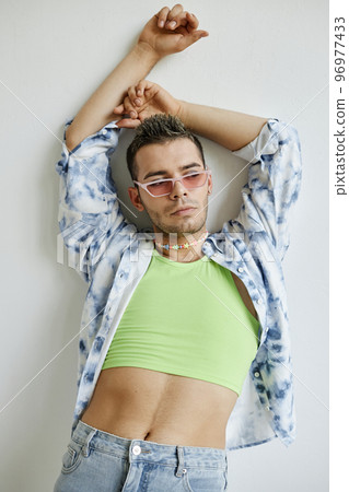 Gay man posing sensually against white wall Gay man posing sensually against white wall 96977433