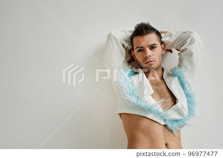 Non binary man leaning on white wall in studio Non binary man leaning on white wall in studio 96977477