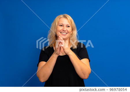 Anticipation of something good idea with a beautiful caucasian woman rubbing her hands together. She is standing on a blue background with copy space. Interesting offer or sale concept Anticipation of something good idea with a beautiful caucasian woman rubbing her hands together. She is standing on a blue background with copy space. Interesting offer or sale concept 96978054