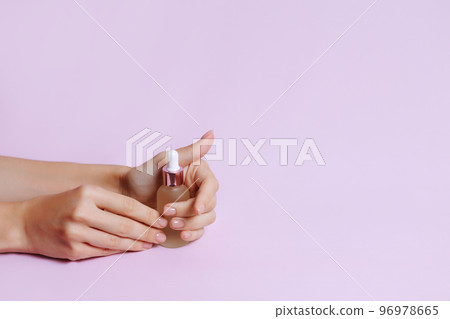 Serum bottle in female hands, side view.  96978665