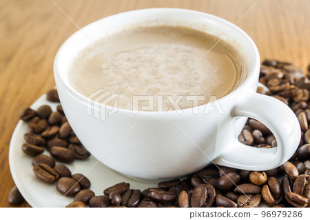 Cup of coffee in a white cup and coffee beans on wooden table background, top view. 96979286