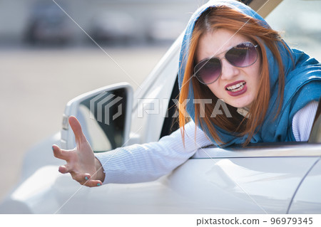 Closeup portrait of pissed off displeased angry aggressive woman driving a car shouting at someone with hand fist up. Negative human expression consept. Closeup portrait of pissed off displeased angry aggressive woman driving a car shouting at someone with hand fist up. Negative human expression consept. 96979345
