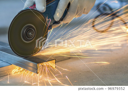Close-up of worker cutting metal with grinder. Sparks while grinding iron. Close-up of worker cutting metal with grinder. Sparks while grinding iron. 96979352