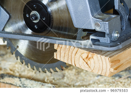 Close-up of new modern powerful circular electrical saw cutting wooden planks. Carpenters tool, construction, repairing and building concept. Close-up of new modern powerful circular electrical saw cutting wooden planks. Carpenters tool, construction, repairing and building concept. 96979383