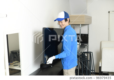 Male worker carrying a TV Male worker carrying a TV 96979435