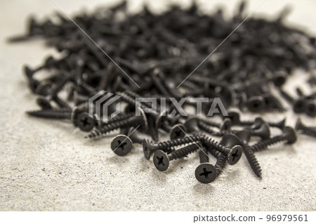 Close-up image of many small black screws on concrete background Close-up image of many small black screws on concrete background 96979561
