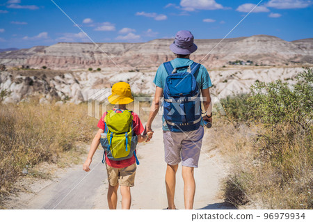 Father and son tourists exploring valley with rock formations and fairy caves near Goreme in Cappadocia Turkey 96979934