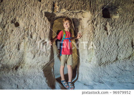 Boy tourist exploring valley with rock formations and fairy caves near Goreme in Cappadocia Turkey Boy tourist exploring valley with rock formations and fairy caves near Goreme in Cappadocia Turkey 96979952