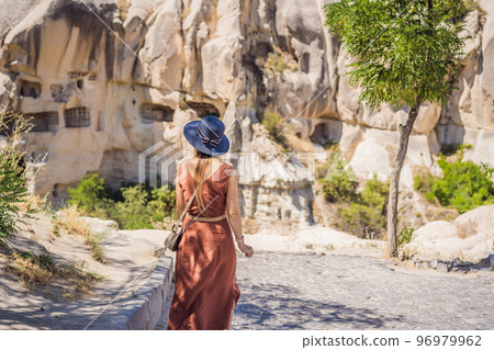 Young woman exploring valley with rock formations and fairy caves near Goreme in Cappadocia Turkey Young woman exploring valley with rock formations and fairy caves near Goreme in Cappadocia Turkey 96979962