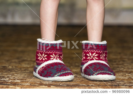 Bare child legs and feet in red winter christmas boots with ornament pattern 96980096