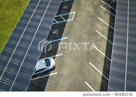 Aerial view of solar panels installed as shade roof over parking lot for parked cars for effective generation of clean electricity. Photovoltaic technology integrated in urban infrastructure 96980236