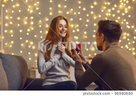 Man in love kneels in front of a girl with a wedding ring in his hands and offers her marriage. Man in love kneels in front of a girl with a wedding ring in his hands and offers her marriage. 96980680