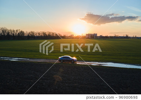 Aerial view of sedan car driving fast on dirt road at sunset. Traveling by vehicle concept. 96980698