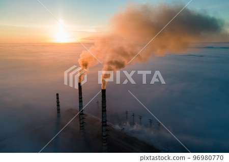Aerial view of coal power plant high pipes with black smoke moving up polluting atmosphere at sunrise. Aerial view of coal power plant high pipes with black smoke moving up polluting atmosphere at sunrise. 96980770