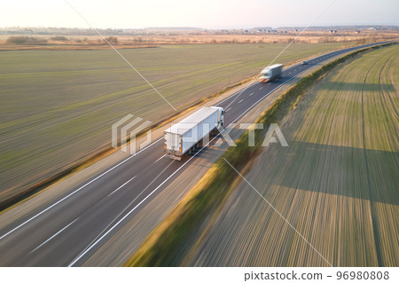 Aerial view of cargo trucks driving on highway hauling goods. Delivery transportation and logistics concept Aerial view of cargo trucks driving on highway hauling goods. Delivery transportation and logistics concept 96980808