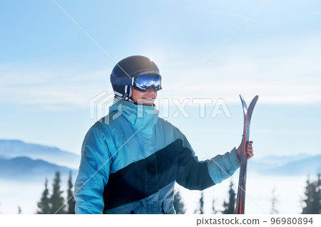 Portrait of a skier in the ski resort on the background of mountains and blue sky, Bukovel.  Ski goggles of a man wearing ski glasses. Winter Sports 96980894