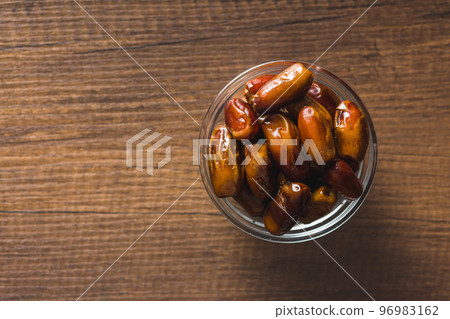 Dried dates fruit in bowl on wooden table. Top view. 96983162