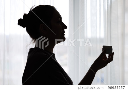 Silhouette of woman smearing hands with moisturizing cream 96983257