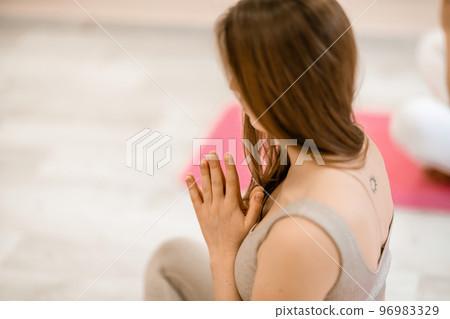 Girl does yoga. Young woman practices asanas on a beige one-ton background. Girl does yoga. Young woman practices asanas on a beige one-ton background. 96983329