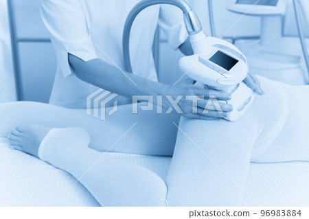 Woman in special white suit getting anti cellulite massage for legs in a spa salon. LPG, and body contouring treatment in clinic. Woman in special white suit getting anti cellulite massage for legs in a spa salon. LPG, and body contouring treatment in clinic. 96983884