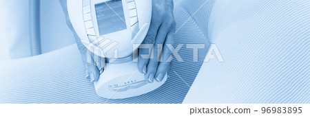 Woman in special white suit getting anti cellulite massage for legs in a spa salon. LPG, and body contouring treatment in clinic. 96983895