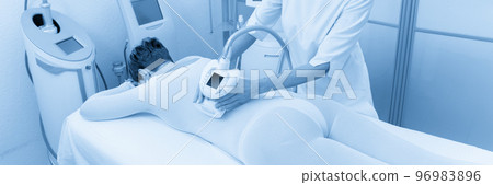Woman in special white suit getting anti cellulite massage in a spa salon. LPG, and body contouring treatment in clinic. Woman in special white suit getting anti cellulite massage in a spa salon. LPG, and body contouring treatment in clinic. 96983896