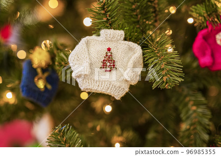 Christmas tree decoration in form of knitted sweater, bokeh garlands. Happy New Year, Xmas card, winter holiday Christmas tree decoration in form of knitted sweater, bokeh garlands. Happy New Year, Xmas card, winter holiday 96985355